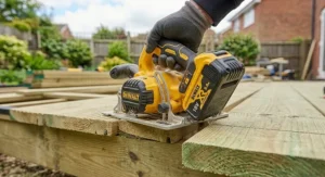 Inserting a fully charged 18V lithium-ion battery into a cordless circular saw for garden deck building.